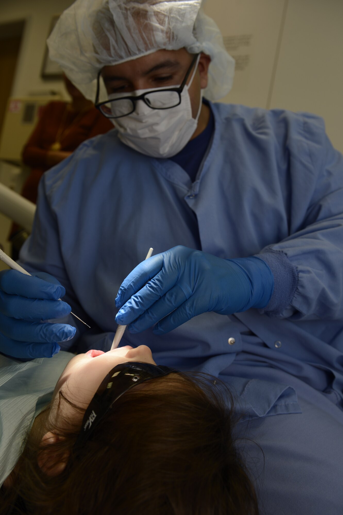 U.S. Air Force Staff Sgt. Ulices Pereira, 52nd Dental Squadron dental logistics NCO in charge, inspects the teeth of Miranda Wright, daughter of Sibel and U.S. Air Force Master Sgt. Nathan Wright, 52nd Medical Support Squadron, during a walk-in children dental clinic at Spangdahlem Air Base, Germany, Oct. 10, 2014. Services provided to the patients included cleanings, X-rays and locating any cavities for future appointments. (U.S. Air Force photo by Staff Sgt. Christopher Ruano/Released)