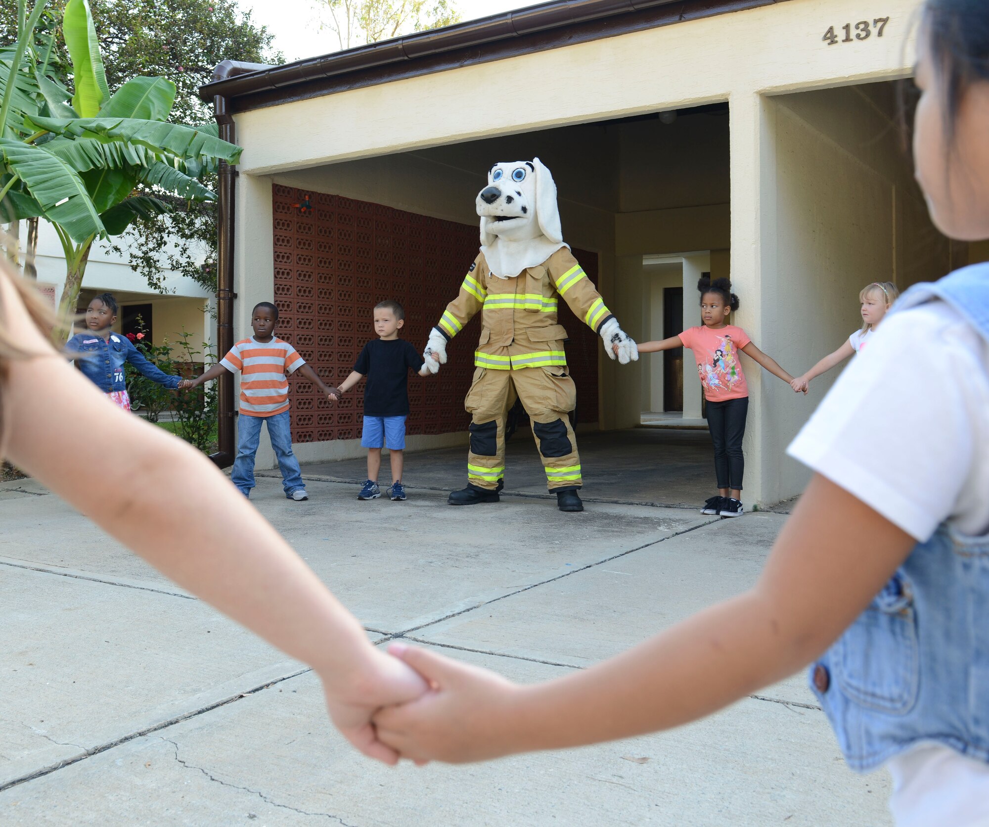 Incirlik Unit School kindergarteners hold hands with Sparky the Fire Dog at a meeting place Oct. 9, 2014, Incirlik Air Base, Turkey. The students learned the importance of knowing the emergency number, and having a safe meeting place in case of a fire during a visit to Sparky’s House. (U.S. Air Force photo by Staff Sgt Eboni Reams/Released)
