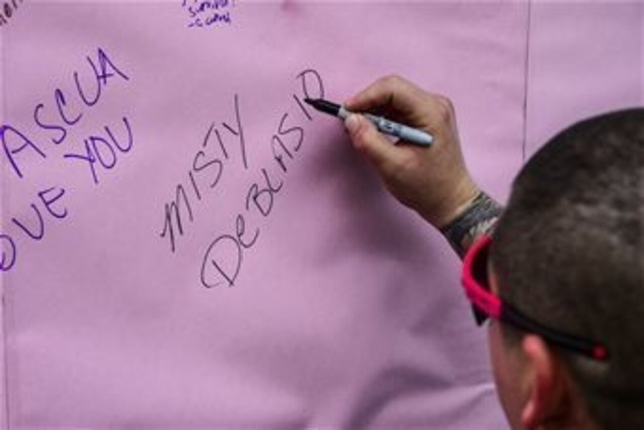 U.S. Army Sgt. India Smith, assigned to the 1-228th Aviation Regiment, writes the name of the person she ran in support of on a poster during the “Think Pink 5K” on Soto Cano Air Base in Honduras, Oct. 9, 2014. The fun run was planned and coordinated by the Morale, Welfare and Recreation Center to help increase breast cancer awareness. U.S. Air Force photo by Tech. Sgt. Heather R. Redman