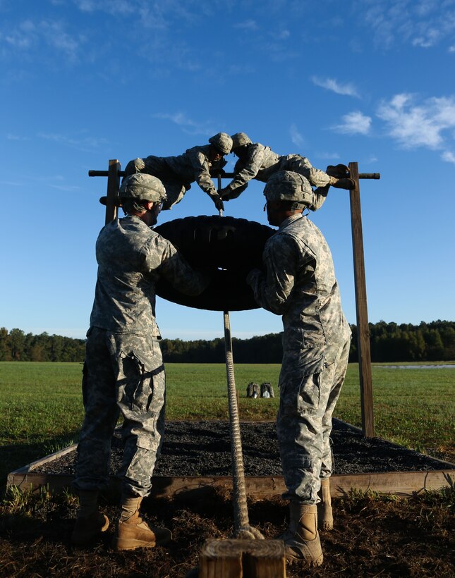 Army Staff Sgt. Jacob West, front left, navigates an obstacle course