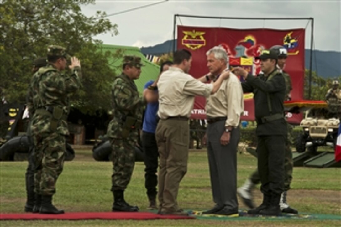 Colombian Defense Minister Juan Carlos Pinzon presents U.S. Defense Secretary Chuck Hagel with the Medalla Fe en la Causa at Tolemaida Air Force Base, Colombia, Oct. 10, 2014, during the secretary's South American trip.