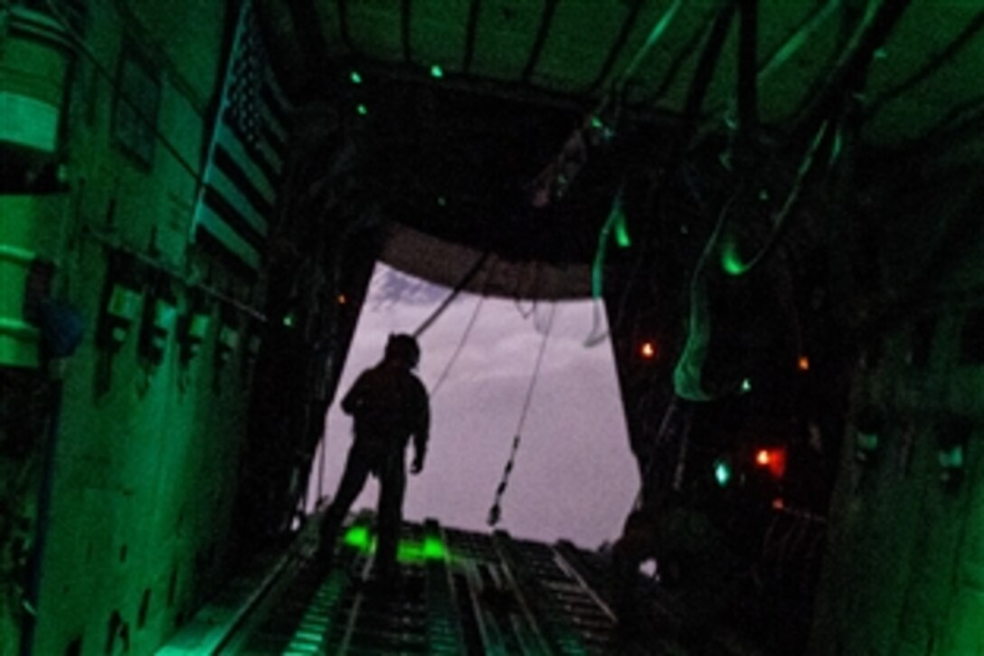 A U.S. Air Force C-130 Hercules airman checks to make sure the containers of bundles cleared the aircraft during a resupply airdrop mission over the region of Bayji, Iraq, Oct. 10, 2014. The C-130 dropped bundles totaling 3,800 meals ready to eat and 1,400 gallons of fresh drinking water. The airman is a loadmaster.