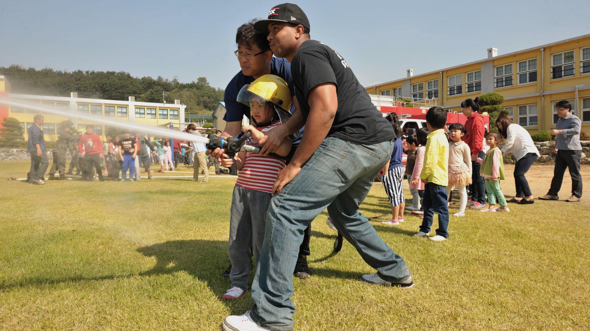 More than 80 Okbong Elementary School children take turns using a water hose as Airmen from the 8th Civil Engineer Squadron and Republic of Korea air force 38th Fighter Group fire departments provide fire safety training alongside Gunsan City fire fighters, Oct. 7, 2014. The 2014 Fire Prevention Week theme is ‘Working smoke alarms save lives, test yours every month.’ As part of fire prevention week, Kunsan Air Base’s fire department conducted more than 10 fire drills and provided fire safety training Oct. 5-11. (U.S. Air Force photo by Senior Airman Katrina Heikkinen/released)
