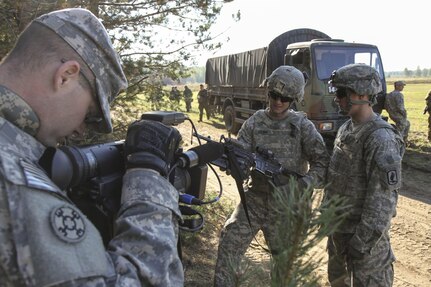 Pennsylvania Army National Guard Staff Sgt. Matthew Keeler of the 109th Mobile Public Affairs Detachment films an interview with forward observer Pfc. Tyler Hanna and gunner Pfc. Tristten Wagner of Able Company, 173rd Airborne Brigade, at Lithuania's Brig. Gen. Kazys Vieverskis Kazlu Rudos Poligonas Center, Sept. 18, 2014. 