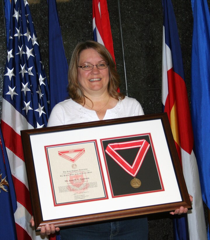 Annette Epperson holds up her Bronze de Fleury medal she received for her more 
than 37 years of dedicated service to the United States Army Corps of 
Engineers. 