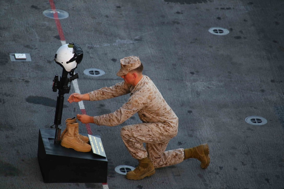Cpl. Rance Powell, crew chief with Marine Medium Tiltrotor Squadron 163 (Reinforced), 11th Marine Expeditionary Unit (MEU), places dog tags on the memorial stand of Cpl. Jordan Spears as part of his memorial on the flight deck of the USS Makin Island (LHD 8), Oct. 8. Cpl. Spears was lost at sea Oct. 1 during flight operations off the Makin Island. The 11th MEU is embarked with the Makin Island Amphibious Ready Group and deployed to maintain regional security in the U.S. 5th Fleet area of responsibility. (U.S. Marine Corps photo by Capt. Joshua Diddams/RELEASED)