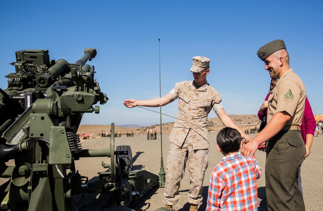 U.S. Marine Cpl. Jonathan Lira, right, shows his son an M777A2 Lightweight Howitzer used by Marines after the composite ceremony for the 15th Marine Expeditionary Unit aboard Camp Pendleton, Calif., Oct. 10, 2014. Lira, 26, from El Paso, Texas, is an administrative specialist with the 15th Marine Expeditionary Unit. (U.S. Marine Corps photo by Sgt. Emmanuel Ramos/Released)