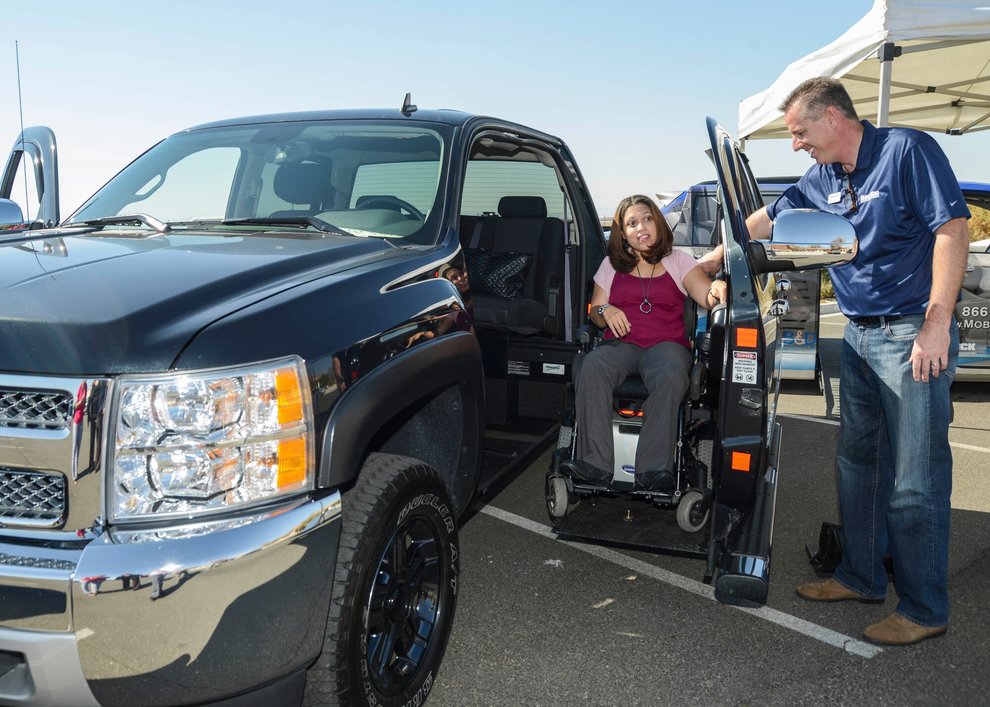 Nicole Carter, an Independent Living Center of Southern California case manager, is assisted by Tim Rosso, Mobility Works certified mobility consultant, in trying out the modified 2012 Chevy Silverado truck. The truck has a lift that will put a person sitting in a wheel chair directly into the driver's side. For Carter, sitting behind the wheel in her wheelchair was a “liberating” experience. (U.S. Air force photo by Rebecca Amber)