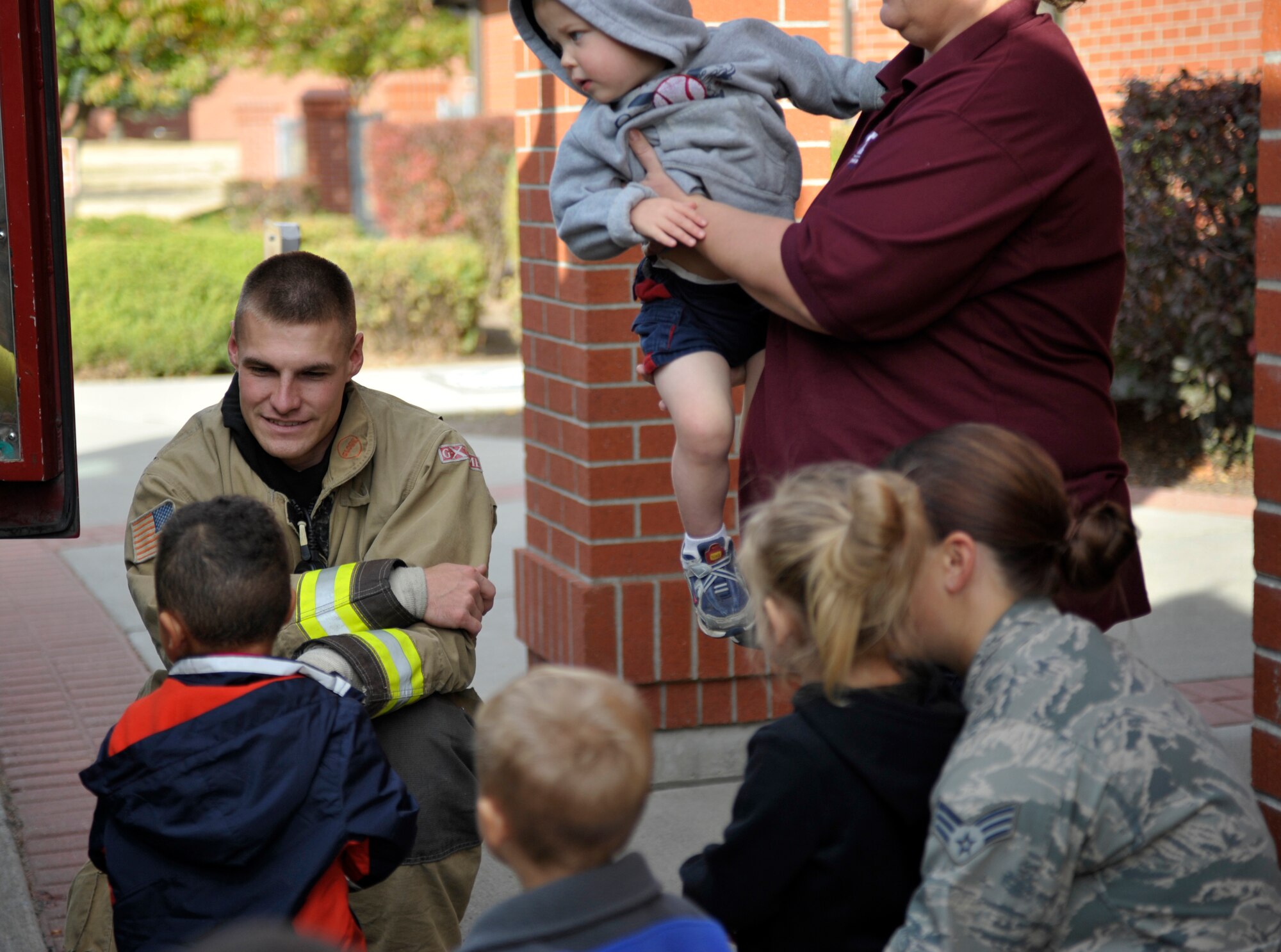 Staff Sgt. Zachary Olds, a  92nd Civil Engineer Squadron firefighter, speaks with children about the fire truck on display at the Child Development Center Oct. 8, 2014, at Fairchild Air Force Base, Washington. During Fire Prevention Week 2014, the base fire department made several trips to the schools on base talking to them about fire safety. (U. S. Air Force photo by Airman 1st Class Taylor Bourgeous)