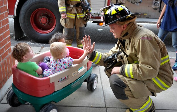 Senior Airman Brandon Eichenlaub, a 92nd Civil Engineer Squadron firefighter, interacts with children from the Child Development Center Oct. 8, 2014, at Fairchild Air Force Base, Washington. The fire department held events for Fire Prevention Week 2014, including visiting children from Michael Anderson Elementary School, a poster drawing contest and tours of the fire department to bring awareness to fire safety and prevention. (U. S. Air Force photo/Airman 1st Class Taylor Bourgeous) 

