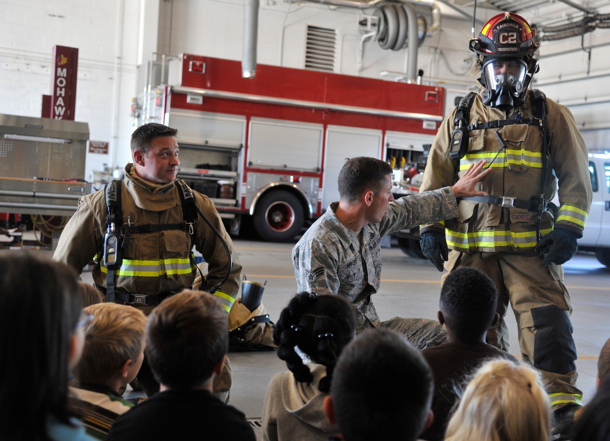 Senior Airman Logan Baker, 92nd Civil Engineer Squadron firefighter, talks to students from Michael Anderson Elementary School about fire protection equipment during a tour of the fire department at Fairchild Air Force Base, Washington, Oct. 6, 2014. The school's visit, along with several other events held during the week, were held to bring awareness to Fire Prevention Week 2014. (U.S. Air Force photo by Senior Airman Mary O'Dell)