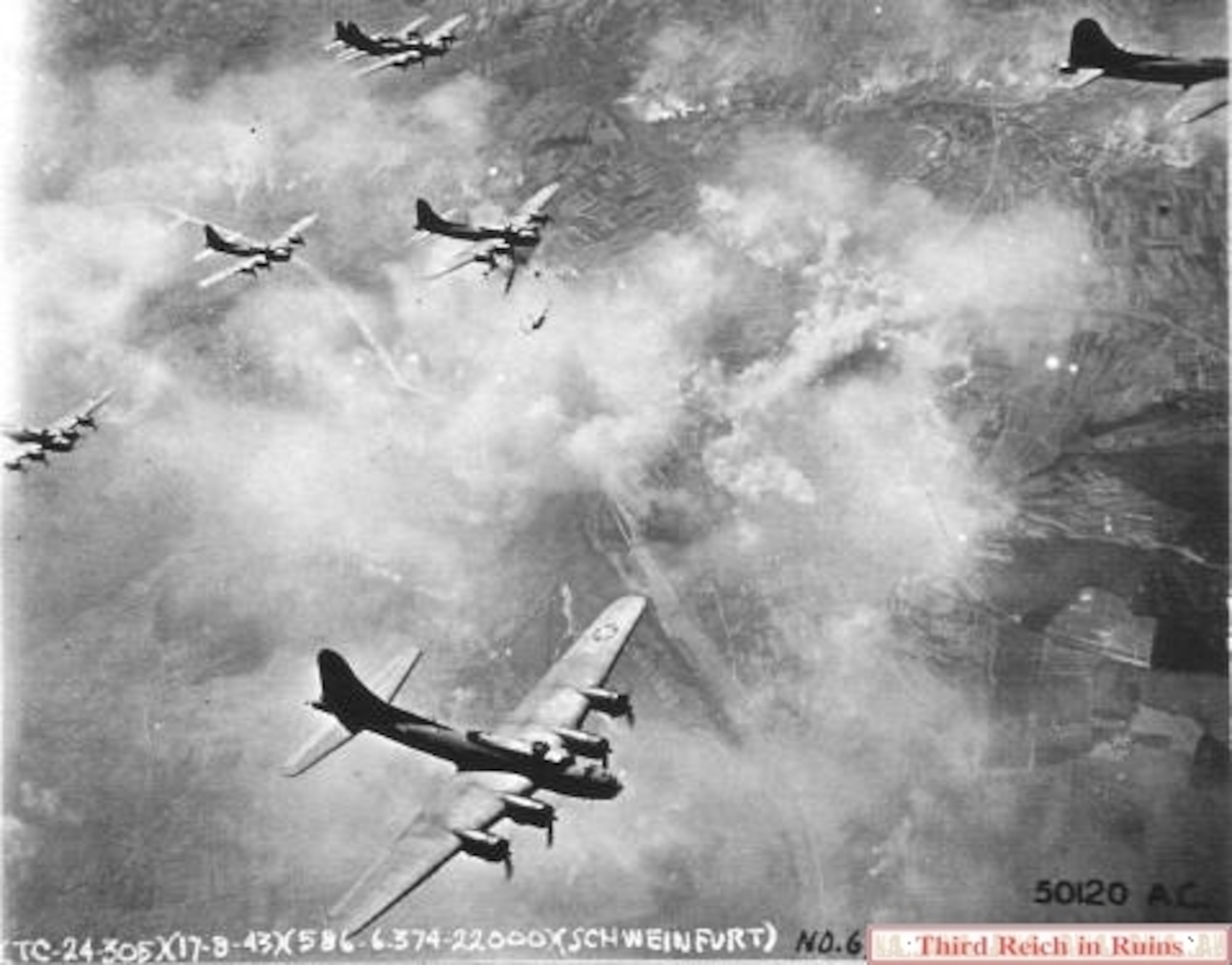 Views of the initial attack on Aug. 17 1943. The city and bearing factories burn after the attack. Visible behind the B-17 at the upper right corner of the photo are numerous smoke trails from smoke generating devices on the ground near the Flugplatz military post, in an effort at camouflage. (U.S. National Archives, RG 342FH-3A22448)