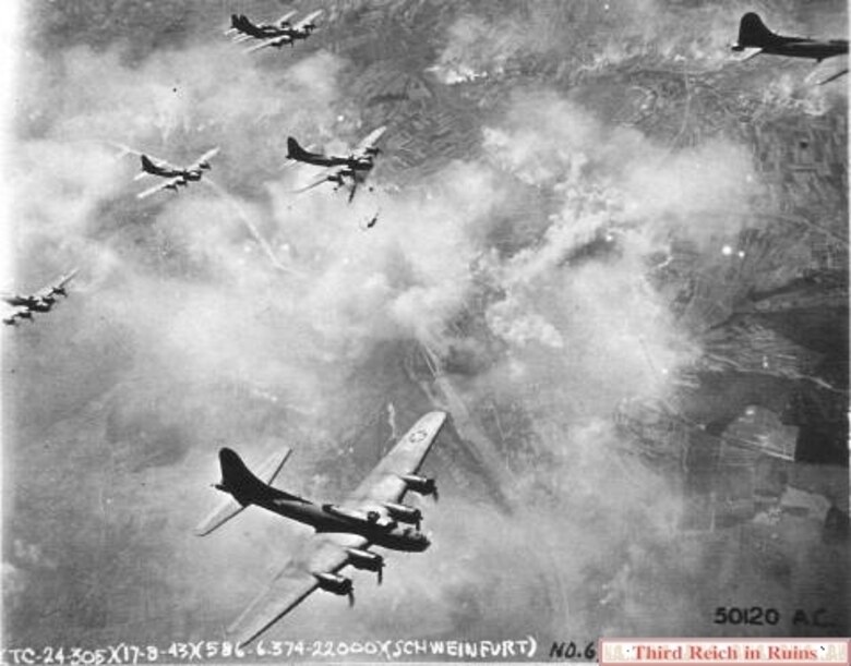 Views of the initial attack on Aug. 17 1943. The city and bearing factories burn after the attack. Visible behind the B-17 at the upper right corner of the photo are numerous smoke trails from smoke generating devices on the ground near the Flugplatz military post, in an effort at camouflage. (U.S. National Archives, RG 342FH-3A22448)