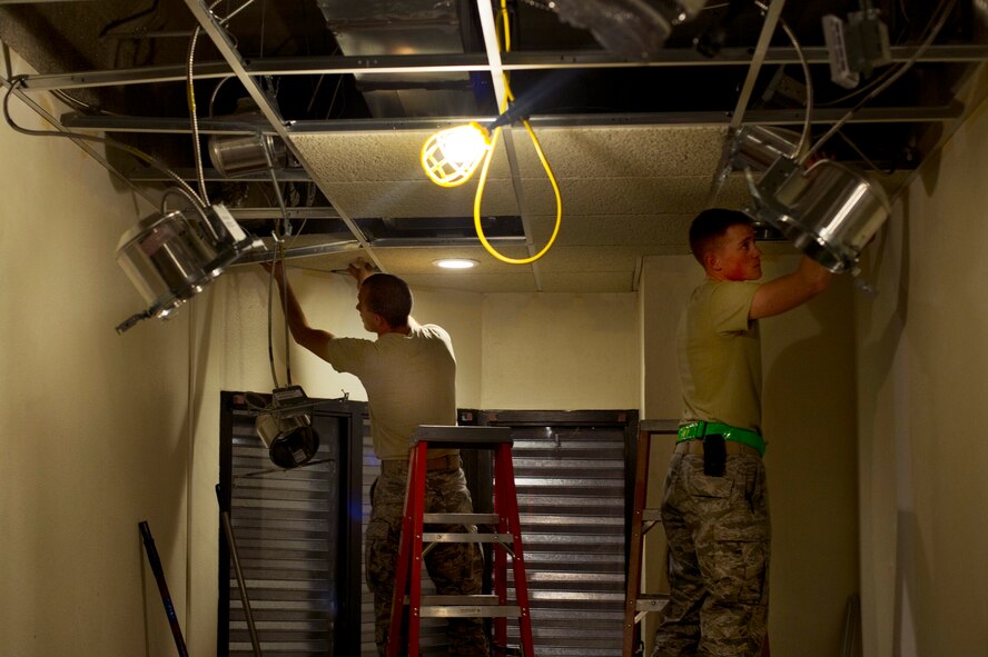 Airmen from the 5th Civil Engineering Squadron replace the ceiling tile of the Law Enforcement Desk on Minot Air Force Base, N.D., Oct. 7, 2014. The LE Desk has been relocated to the fire department dispatch office until the renovations are finished. (U.S. Air Force photo/Senior Airman Brittany Y. Bateman)