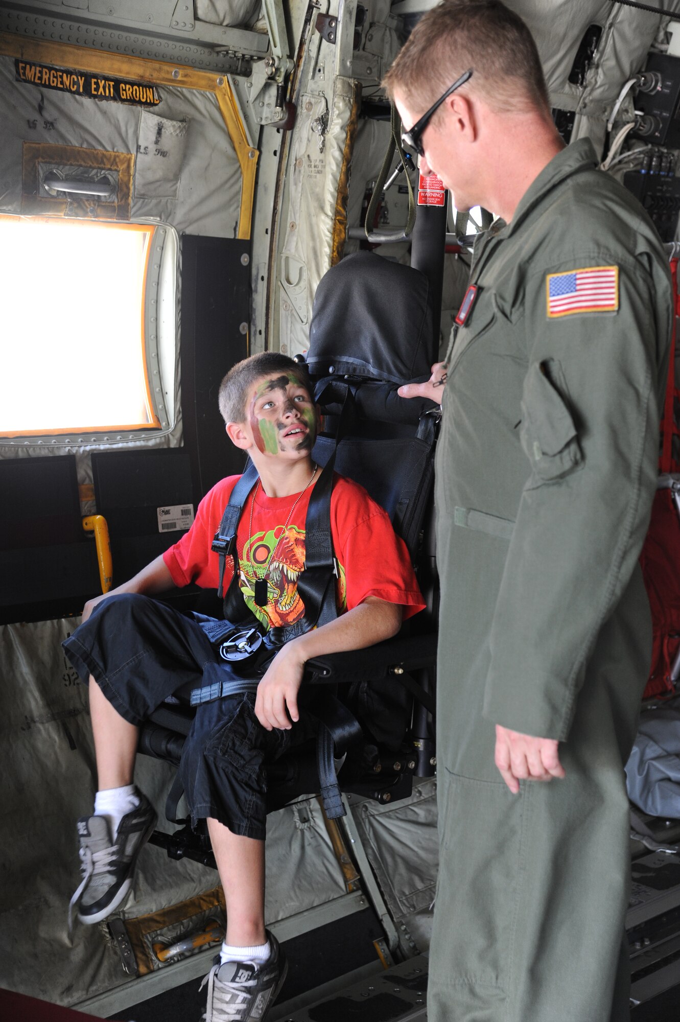 The son of Staff Sgt. James Nottle, 338th Training Squadron, sits in a loadmaster crash-worthy seat on a C-130J aircraft as he listens to Chief Master Sgt. Rick Cumbo, 403rd Operations Group, explain how it works during Operation Hero Oct. 11, 2014, at Keesler Air Force Base, Miss.  The event was designed to help children better understand what happens when their parents deploy.  (U.S. Air Force photo by Kemberly Groue)