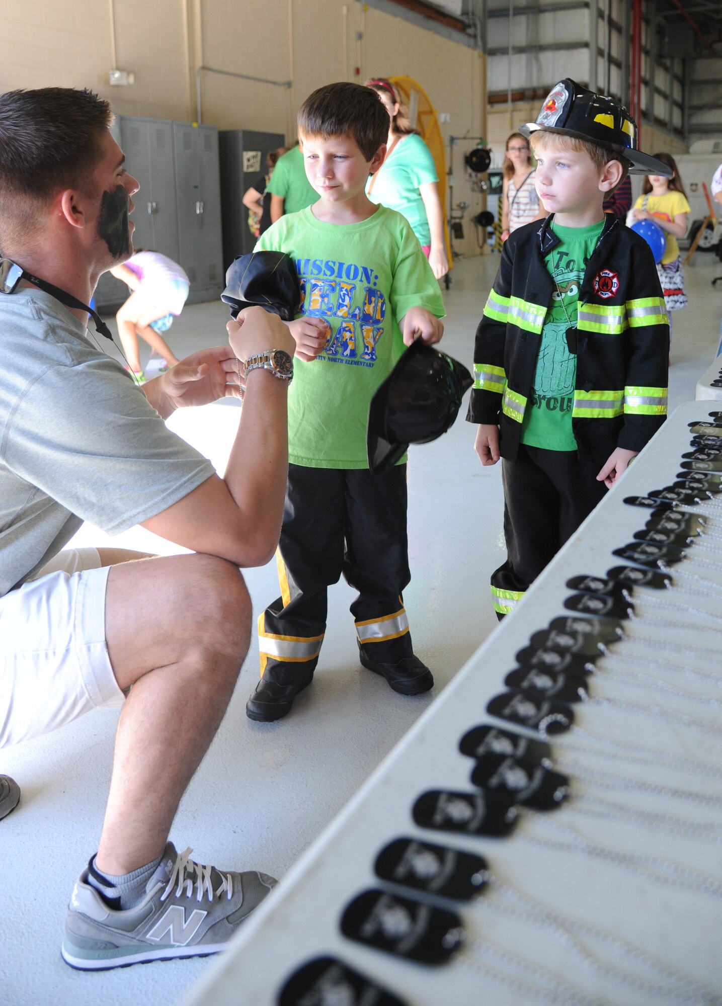 Airman 1st Class Joseph Waldrop, 81st Medical Support Squadron, hands out dog tags and t-shirts to the sons of Senior Airman Jesse Peterson, 81st Security Forces Squadron, during Operation Hero Oct. 11, 2014, at Keesler Air Force Base, Miss.  The event was designed to help children better understand what happens when their parents deploy.  (U.S. Air Force photo by Kemberly Groue)