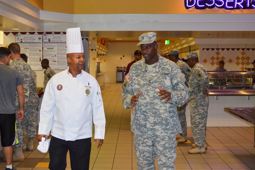 U.S. Army Chief Charles H. Talley Jr., Joint Culinary Center of Excellence instructor, and Master Sgt. Orlando G. Akins, 7th Transportation Brigade (Expeditionary) senior management noncommissioned officer, takes a tour through the Resolute Dining facility at Fort Eustis, Va., Oct. 1, 2014. The JCCoE partnered with the Resolute team to enhance food presentation and boost morale in the Resolute Dining Facility. (U.S. Army photo by Spc. Marian Alleva/Released)