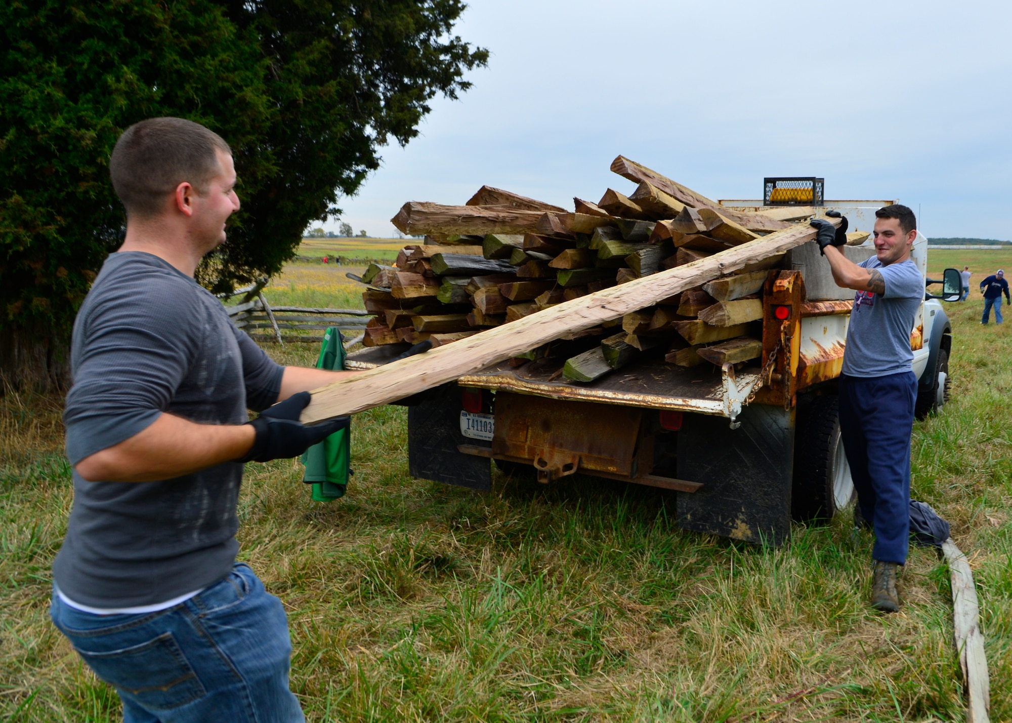 Staff Sgt. Caleb Dubourg, left, 436th Maintenance Squadron aerospace pulse technician, and Senior Airman Robert Money, right, 436th MXS aerospace journeyman, unload a wood railing to replace rotted sections of fence Oct. 10, 2014, at Gettysburg National Military Park, Pa. Volunteers helped to clear brush and replace wood railings on a 300-yard section of fence behind the Sherfy House. (U.S. Air Force photo/Airman 1st Class William Johnson)