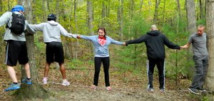 Airmen hold hands with one another while balancing on a wire during a Joint Base Andrews Resiliency Retreat at Wilderness Adventure at Eagle Landing in New Castle, Va., Sept. 29, 2014. The Airmen were instructed to cross a wire between trees without touching the ground. (U.S. Air Force photo/Tech. Sgt. Krystal Cruz)