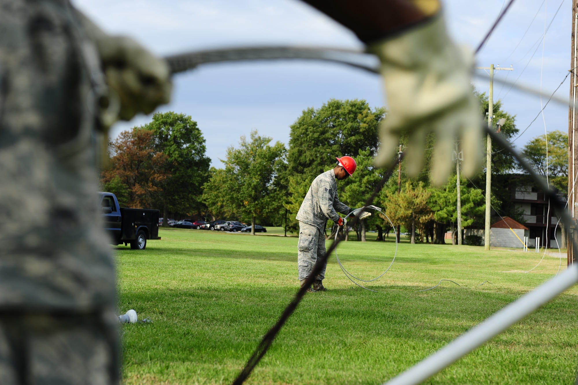 U.S. Air Force Senior Airman Theodore Sebsibe, 633rd Civil Engineer Squadron electrician, rolls up inactive power lines after taking them down at Langley Air Force Base, Va., Oct. 10, 2014. Members of the 633rd CES rotated jobs while taking down the lines to gain experience in various areas of the activity. (U.S. Air Force photo by Staff Sgt. Natasha Stannard/Released)