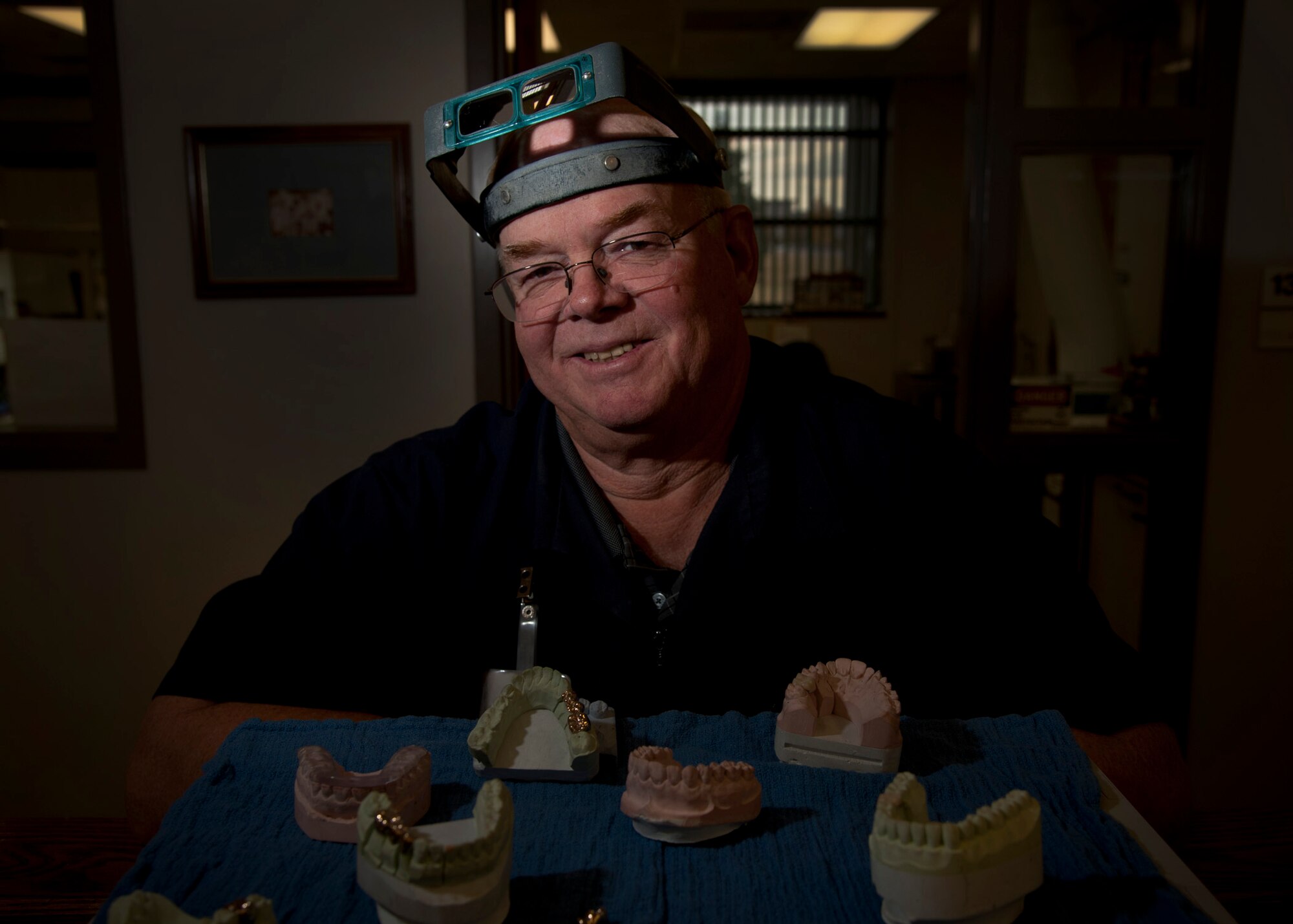 PETERSON AIR FORCE BASE, Colo. – Ron Hill, 21st Space Wing Area Dental Lab certified dental technician, poses with an array of dental appliances at the Peterson AFB Area Dental Lab Oct. 9, 2014. Peterson’s ADL supports 121 Department of Defense installations world-wide. The latest dental appliance manufacturing methods allow products like bridges and crowns to be created in mere hours rather than days. (U.S. Air Force photo/Staff Sgt. Aaron Breeden)