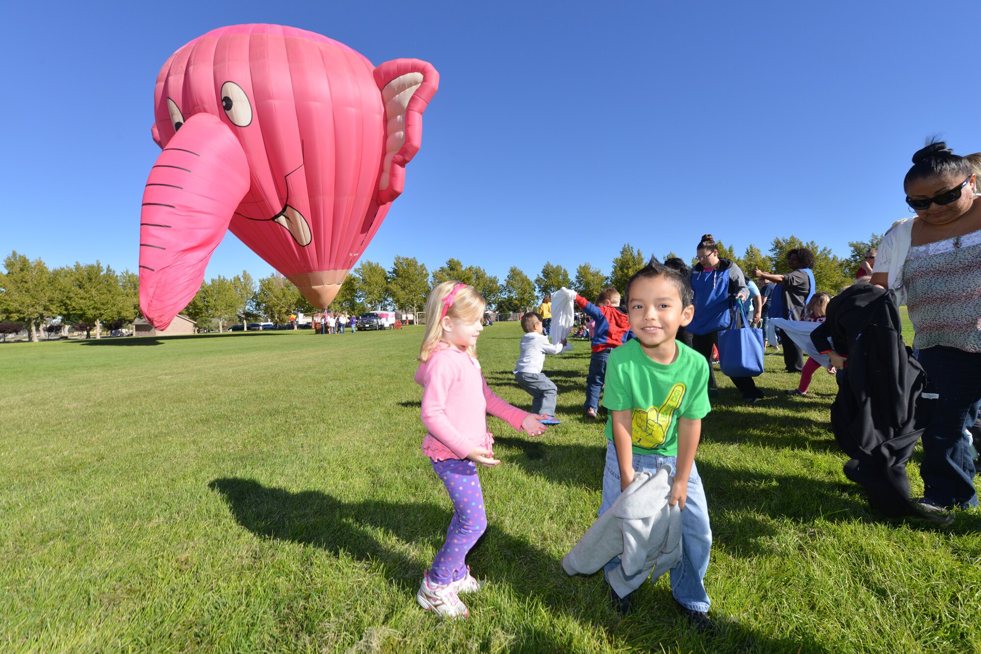 Eliezer Pino, in the green shirt, joins the other children from Kirtland’s Child development Center on Gibson to watch as a hot air balloon is inflated at Hardin Field on Oct. 10. Peter Van Overwalle, owner of the Nelly-B hot air balloon, comes to Albuquerque each year for Balloon Fiesta and always makes a stop at the base to show off his balloon to the children. (Photo by Todd Berenger)