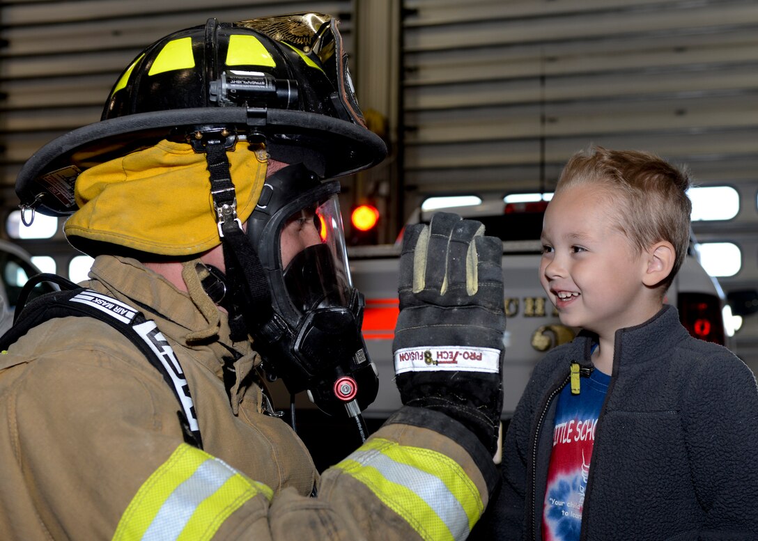 Senior Airman Kyle Gregory, 28th Civil Engineer Squadron firefighter, shows children the safety gear he wears when combating fires from Little Scholar Preschool, Box Elder, S.D., at Ellsworth Air Force Base, S.D., Oct. 9, 2014. Ellsworth firefighters treated the preschoolers to a tour of the firehouse while also teaching them the basics of fire prevention and safety in support of National Fire Prevention Week. (U.S. Air Force photo by Senior Airman Anania Tekurio/Released)