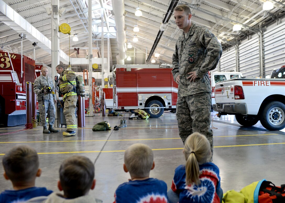 Staff Sgt. Matthew Wright, 28th Civil Engineer Squadron firefighter, explains the safety gear and equipment firefighters use to children from the Little Scholar Preschool, Box Elder, S.D., at Ellsworth Air Force Base, S.D., Oct. 9, 2014. As part of National Fire Prevention Week, Ellsworth firefighters visited and spoke to students from several local schools about fire safety, fire prevention and what steps to take during a real fire situation. (U.S. Air Force photo by Senior Airman Anania Tekurio/Released)