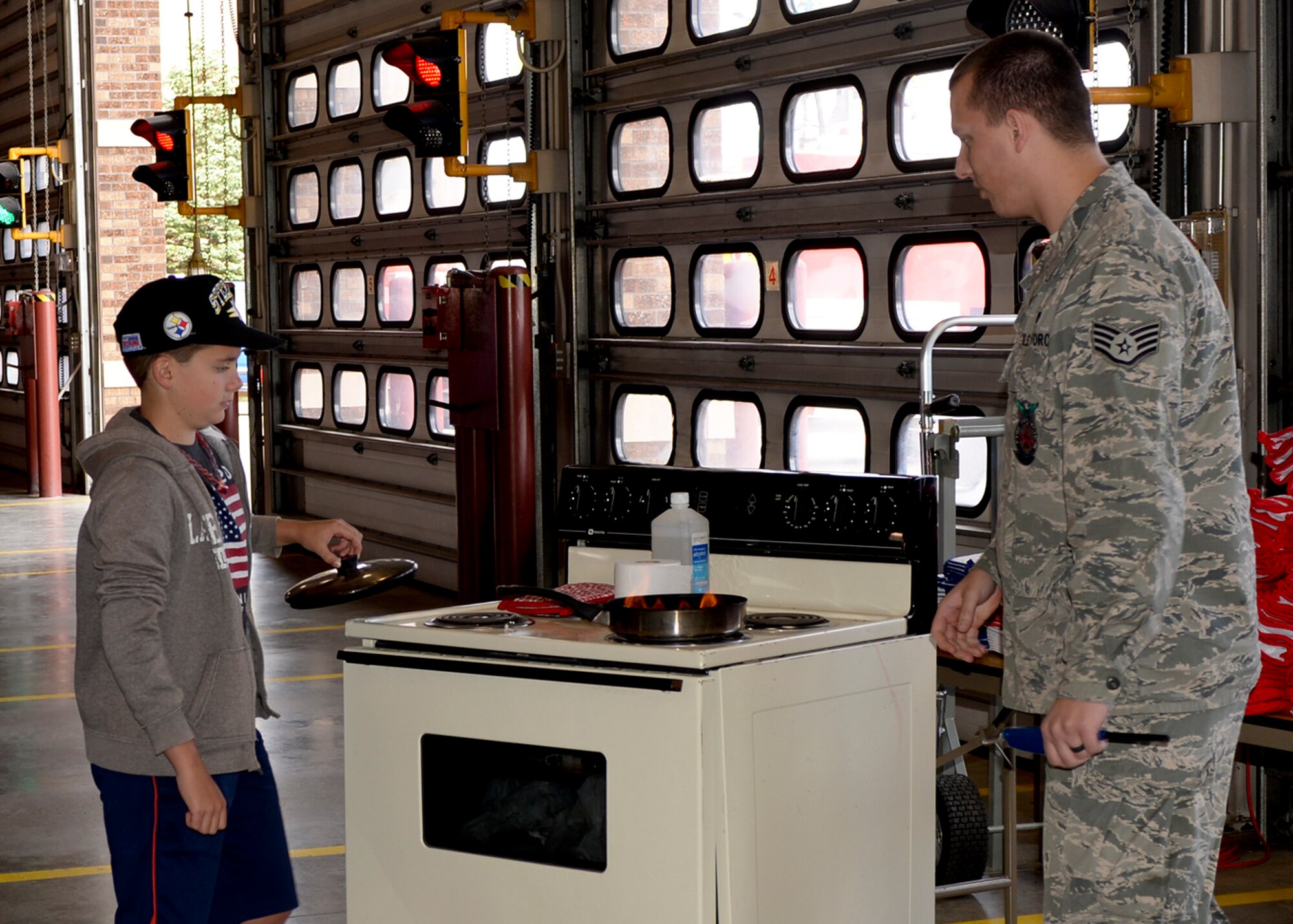 Staff Sgt. Brian Dvorak, 28th Civil Engineer Squadron firefighter, teaches children how to properly and safely handle a stove top fire during a National Fire Prevention Week open house at Ellsworth Air Force Base, S.D., Oct. 4, 2014. This year’s theme focuses on testing your fire alarms monthly to save lives and included a firefighter challenge event, a parade through base housing, and firefighters visiting area schools to talk about fire safety.  (U.S. Air Force photo by Senior Airman Anania Tekurio/Released)