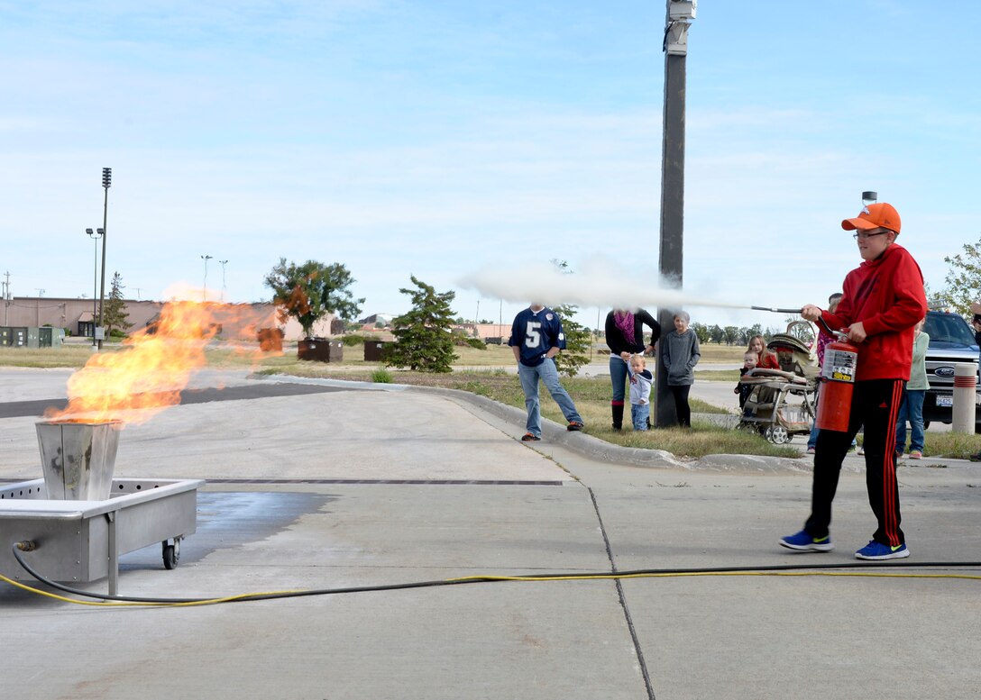 Children had the opportunity to put out a controlled fire using a fire extinguisher during a National Fire Prevention Week open house at Ellsworth Air Force Base, S.D., Oct. 4, 2014. The activity allowed children to learn how to properly extinguish a fire and the safety procedures to follow in a real fire situation. (U.S. Air Force photo by Senior Airman Anania Tekurio/Released)