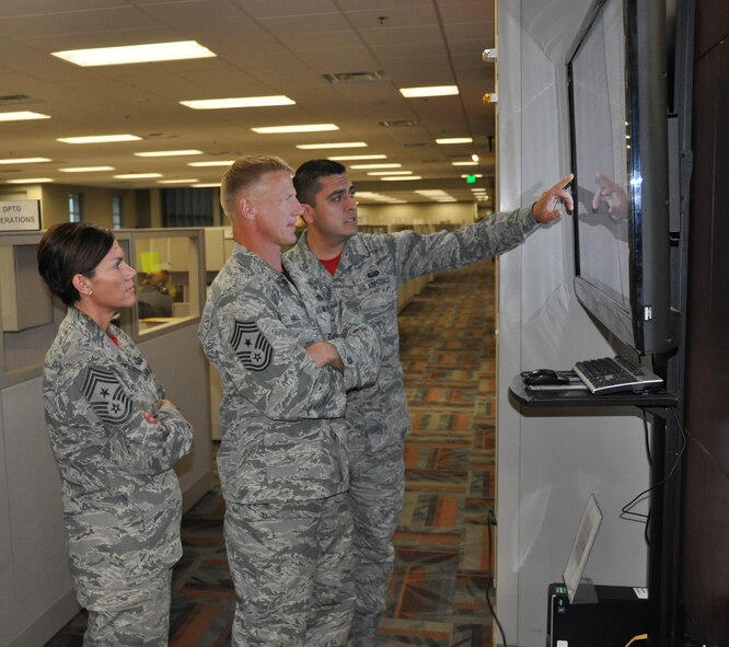 Senior Airman Samuel Uribe-Talamantes, Air Reserve Personnel Center status systems technician, briefs Chief Master Sgt. Craig Hall, 460th Space Wing command chief, on the ARPC call center agents’ log time and ready, non-ready status screen as Chief Master Sgt. Ruthe Flores, ARPC command chief, stands by Oct. 10, 2014, on Buckley Air Force Base, Colo. Hall came to ARPC to say farewell to service members and civilians, thanking them for their service and letting them know the impact they left on him. (U.S. Air Force photo/Tech. Sgt. Rob Hazelett) 