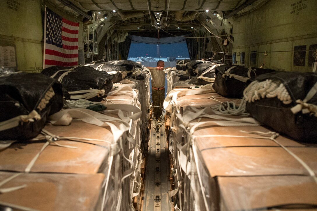 A U.S. Air Force C-130 Hercules airman checks to ensure containers filled with meals, ready to eat and fresh water sit on a C-130 Hercules aircraft in preparation for an operational resupply airdrop near the area of Bayji, Iraq, Oct. 10, 2014. The C-130 dropped bundles totaling 3,800 meals and 1,400 gallons of water. The airman is a loadmaster.