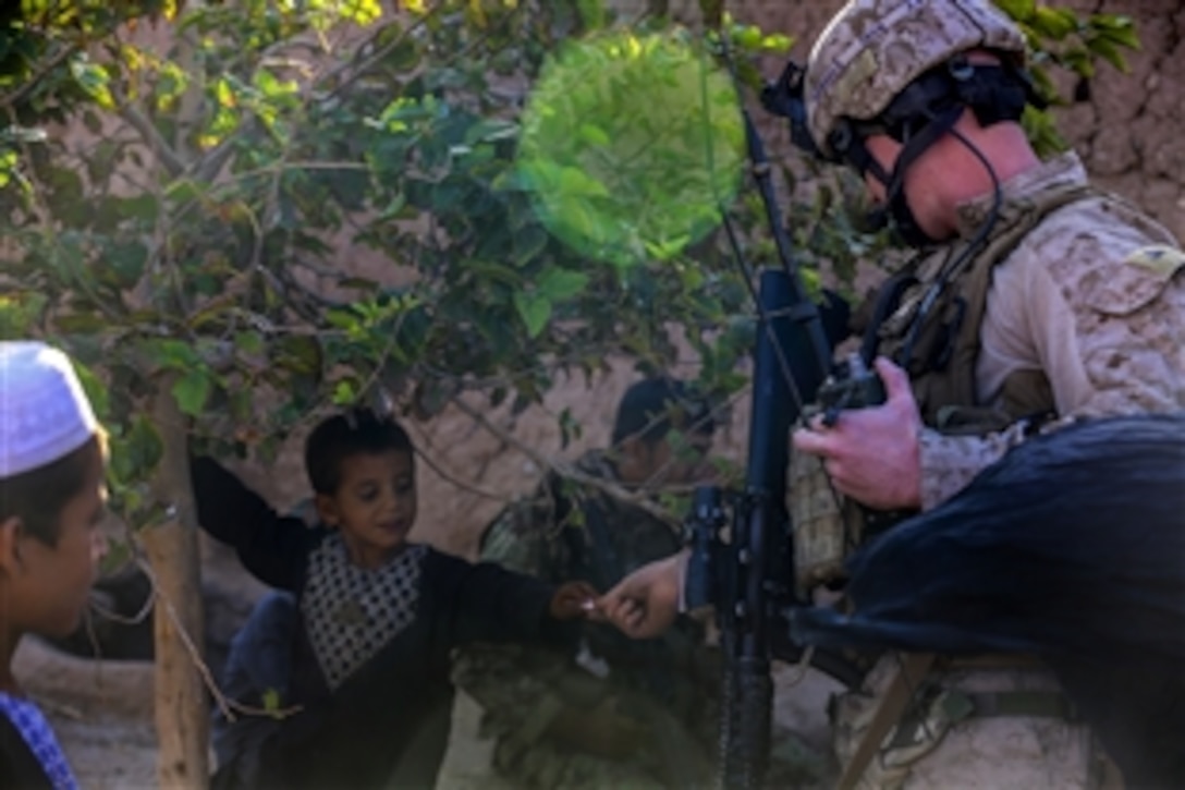 U.S. Marine Corps Cpl. Samuel Nabholz gives candy to a local Afghan child during a security patrol in Nad Ali district in Helmand province, Afghanistan, Oct. 7, 2014. Nabholz is a joint fires observer assigned to Bravo Company, 1st Battalion, 2nd Marine Regiment.