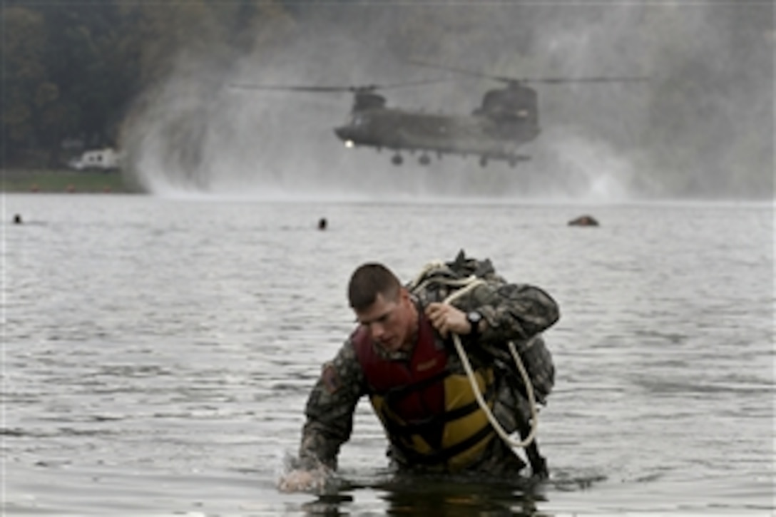 Army Sgt. Max Wolfer exits the water carrying his rucksack after jumping from a CH-47 Chinook helicopter into American Lake on Joint Base Lewis-Mcchord, Wash., Oct. 9, 2014. Wolfer is a combat engineer assigned to 571st Sapper Company, 864th Engineer Battalion.