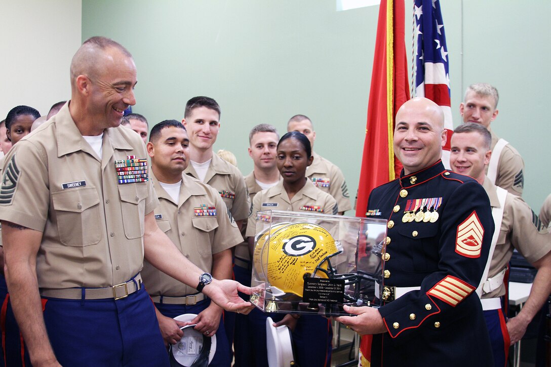 U.S. Marine Corps Gunnery Sgt. John D. Ward, right, receives a retirement gift from U.S. Marine Corps Sgt. Maj. William Sweeney, Recruiting Station Frederick’s sergeant major, before the start of his retirement ceremony in Frederick, Maryland, Sept. 25, 2014. Ward, a career recruiter, retired after 20 years of service. The Green Bay Packers helmet was signed by the many Marines who have worked tirelessly by Ward’s side during his tour as a recruiter and staff noncommissioned officer in charge. (U.S. Marine Corps photo by Cpl. Amber Williams/Released) 