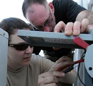 Senior Master Sgt. John Swearingen, superintendant of the 176th Civil Engineer Squadron's Electrical Section, provides guidance to Tech. Sgt. Christine Dick, one of the squadron's heating, ventilation and air conditioning technicians, as she repairs a faulty air conditioning unit Feb. 9, 2010. The squadron is in Puerto Rico for two weeks to train its members on a wide range of infrastructure projects and other upgrades.