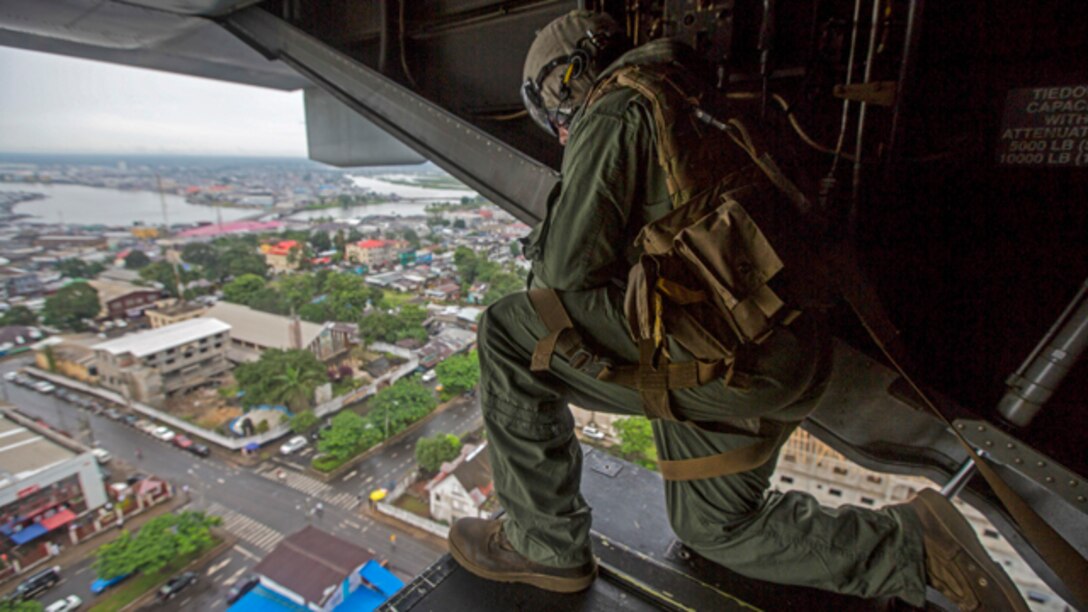 U.S. Marine Corps Cpl. Anthony Kite, assigned to Special-Purpose Marine Air-Ground Task Force - Crisis Response - Africa, looks out of an MV-22B Osprey as they prepare to land at the U.S. Embassy in Monrovia while supporting Operation United Assistance in Monrovia, Liberia, Oct. 13, 2014. Operation United Assistance is part of a comprehensive U.S. Government effort, led by the U.S. Agency for International Development, to respond to and contain the outbreak of the Ebola virus in West Africa as quickly as possible. (U.S. Marine Corps photo by Lance Cpl. Andre Dakis/SP-MAGTF Crisis Response - Africa Combat Camera/Released)