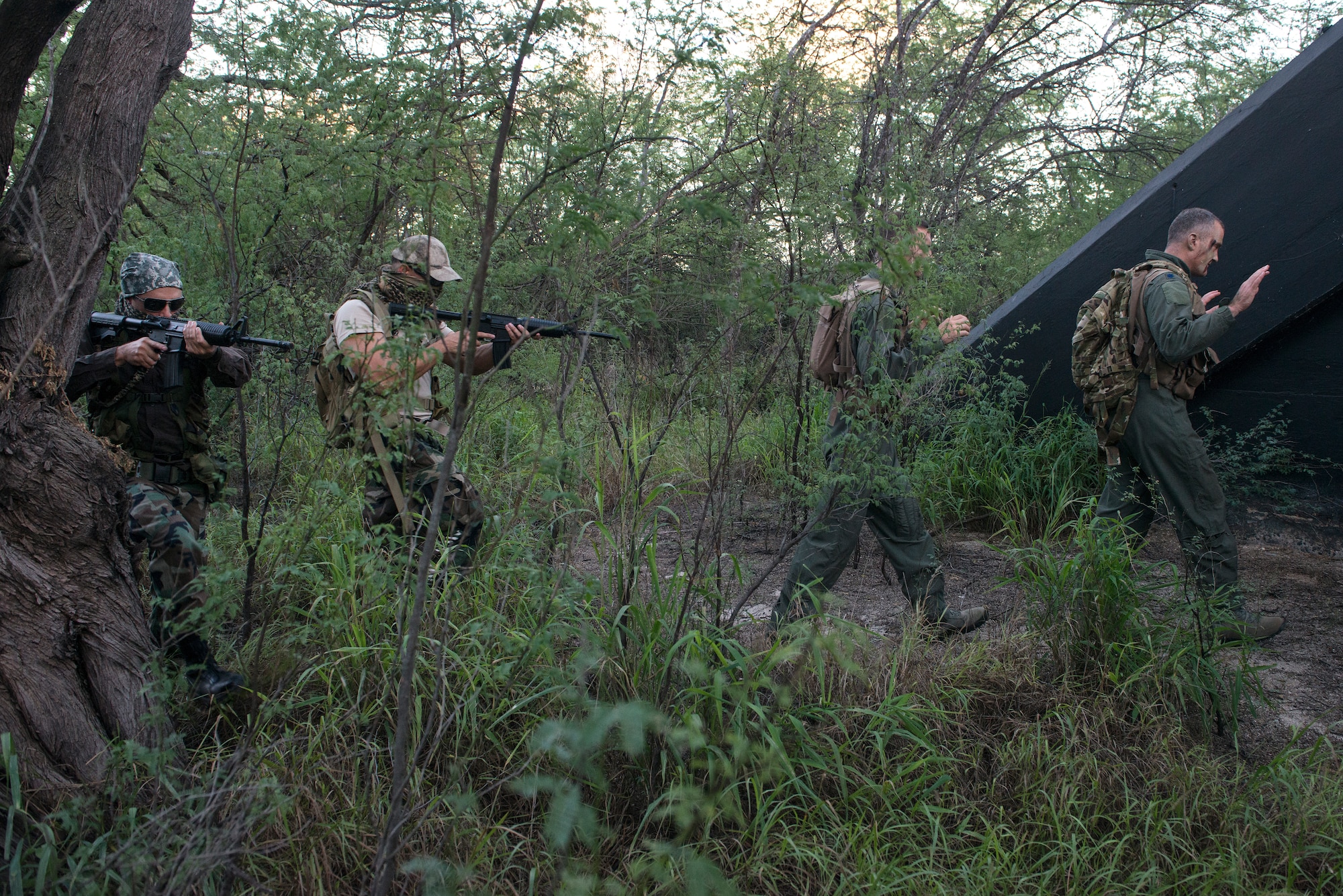 Aircrew members simulate being captured by a mock adversary during a combat survival refresher course Oct. 9, 2014, at Joint Base Pearl Harbor-Hickam, Hawaii. The survival, evasion, resistance and escape combat survival refresher course is designed to familiarize aircrew members with combat skills learned through hands-on training in a realistic environment. SERE is a program that provides training in evading capture, survival skills and the military code of conduct. (U.S. Air Force photo/Staff Sgt. Christopher Hubenthal)