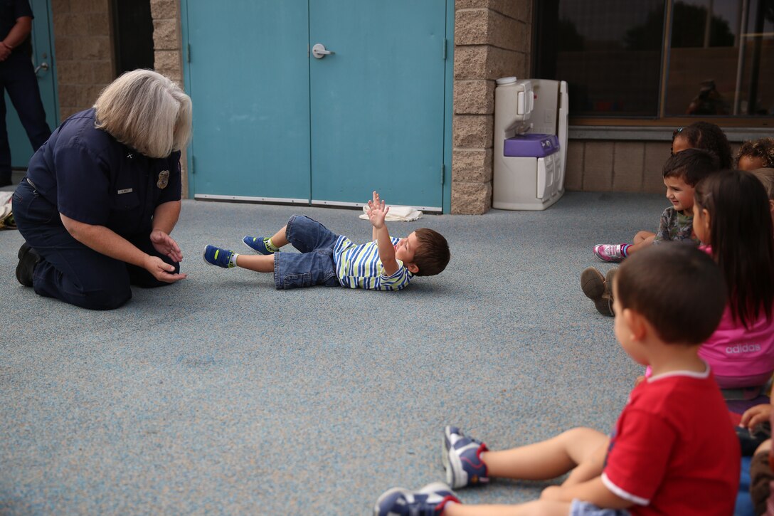 Susan Belt, a fire inspector with the Miramar Fire Department, teaches children at the Child Development Center how to stop, drop and roll during a fire safety class aboard Marine Corps Air Station Miramar, Calif., Oct. 14. Firefighters teach these lessons while they are young to help develop good fire safety habits for their futures. 