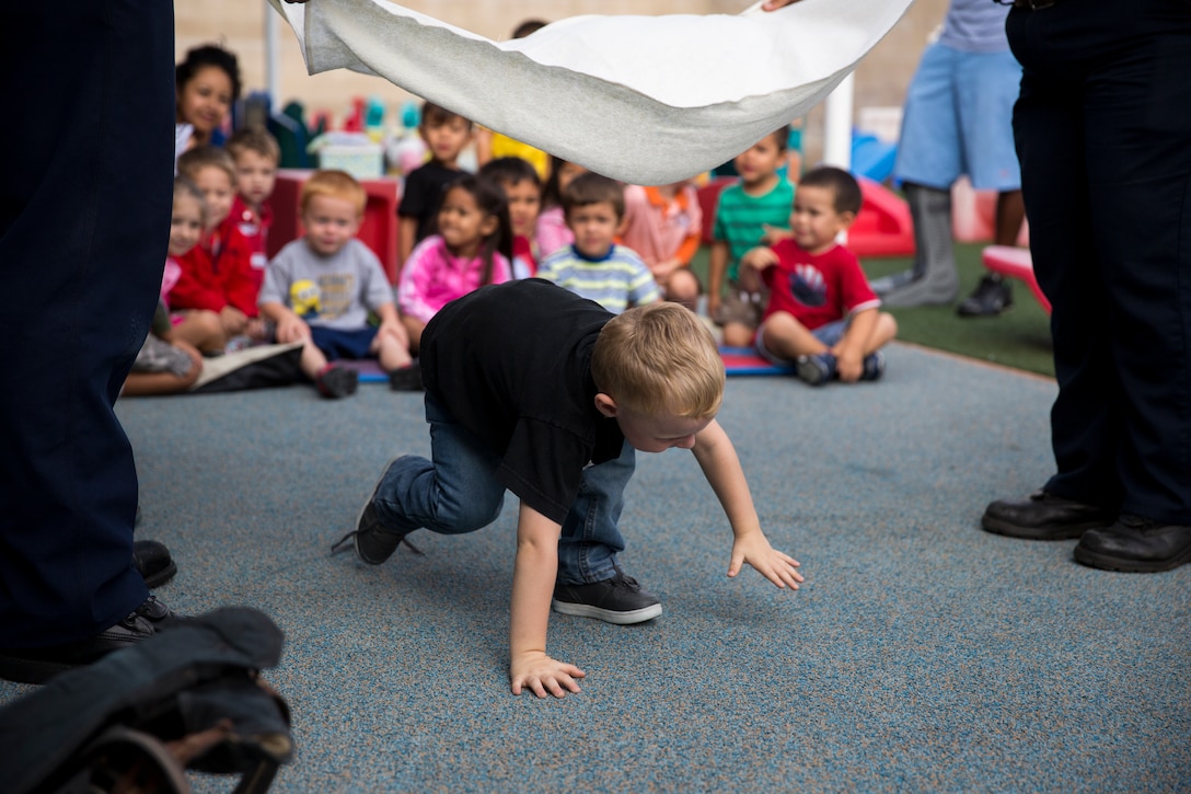 A preschool student practices crawling under smoke during a fire safety class aboard Marine Corps Air Station Miramar, Calif., Oct. 14. Firefighters from the Miramar Fire Department also showed children from the Child Development Center what smoke alarms are, what firefighters look like with all of their gear and how to stop, drop and roll. 