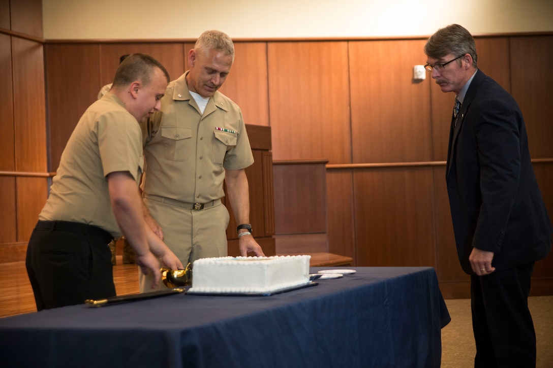 Petty Officer 3rd Class Travis Land, the most junior Sailor at the ceremony,  and Cmdr. Steven Bartell, the most senior Sailor at the ceremony, cut the cake and offer the first piece to Steve McMurtry, the guest of honor, as part of the traditional cake cutting ceremony. At celebrations from ships to shore, the Navy’s birthday cake is cut by the most senior and the most junior sailor at the same time. The tradition represents passing knowledge and experience from one generation to the next.