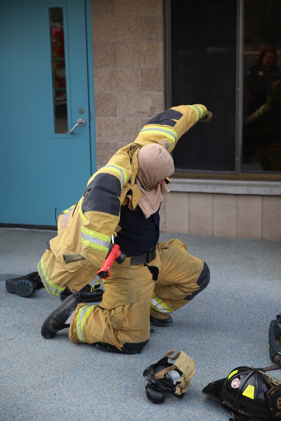 A firefighter with the Miramar Fire Department puts on his gear during a fire safety class aboard Marine Corps Air Station Miramar, Calif., Oct. 14. The class taught preschool children what a smoke alarm was for, how to move through smoke and how to stop, drop and roll. 