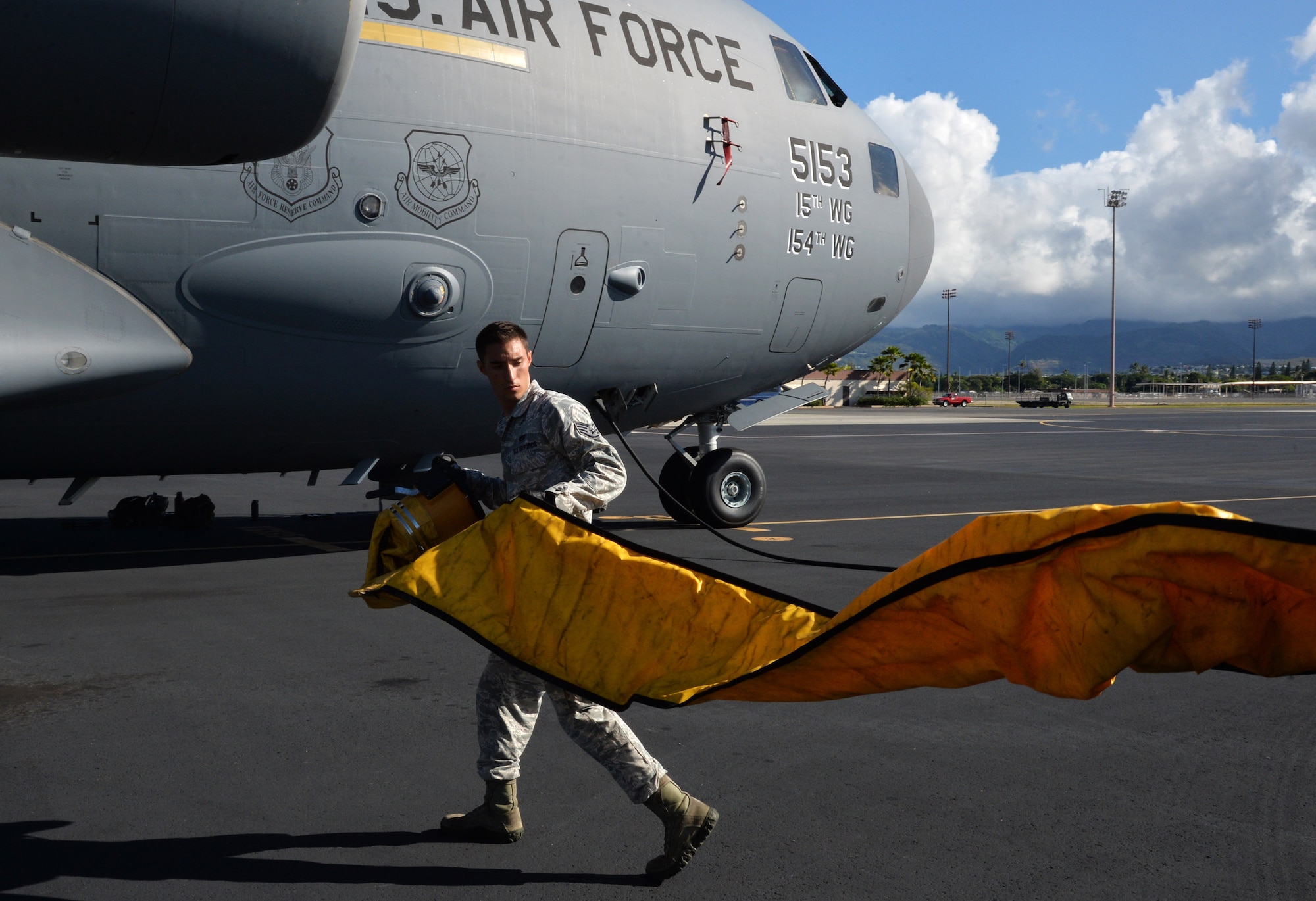 Staff Sgt. Lee Taylor, 15th Aircraft Maintenance Squadron C-17 Globemaster III crew chief, unfolds an airflow line from a mobile air conditioning unit to a C-17 aircraft Oct. 9, 2014, at Joint Base Pearl Harbor-Hickam, Hawaii. The A/C unit keeps the mechanical components cool during hot weather. Taylor oversees the maintenance and inspection work on C-17 aircraft. (U.S Air Force photo by Staff Sgt. Alexander Martinez)