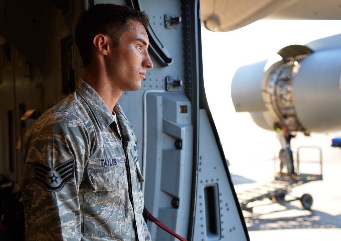 Staff Sgt. Lee Taylor, 15th Aircraft Maintenance Squadron C-17 Globemaster III crew chief, observes the flightline while hydraulic maintenance technicians work on the aircraft in the background Oct. 9, 2014, at Joint Base Pearl Harbor-Hickam, Hawaii. Taylor oversees the maintenance and inspection work on C-17 aircraft. (U.S Air Force photo by Staff Sgt. Alexander Martinez)