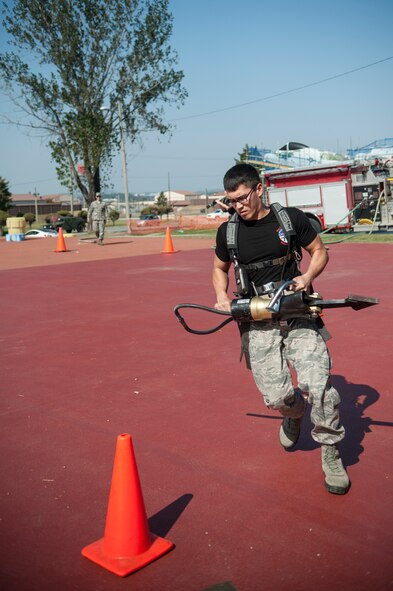 1st Lt. Andrew Davenport, member of team miscellaneous, does the tool serpentine carry during the Firefighter Challenge for Fire Prevention Week at Osan Air Base, Republic of Korea, Oct. 10, 2014. The challenge consisted of five obstacles; the bongo push, tool serpentine carry, hose pull, dummy drag and bucket brigade. (U.S. Air Force photo by Senior Airman Matthew Lancaster)