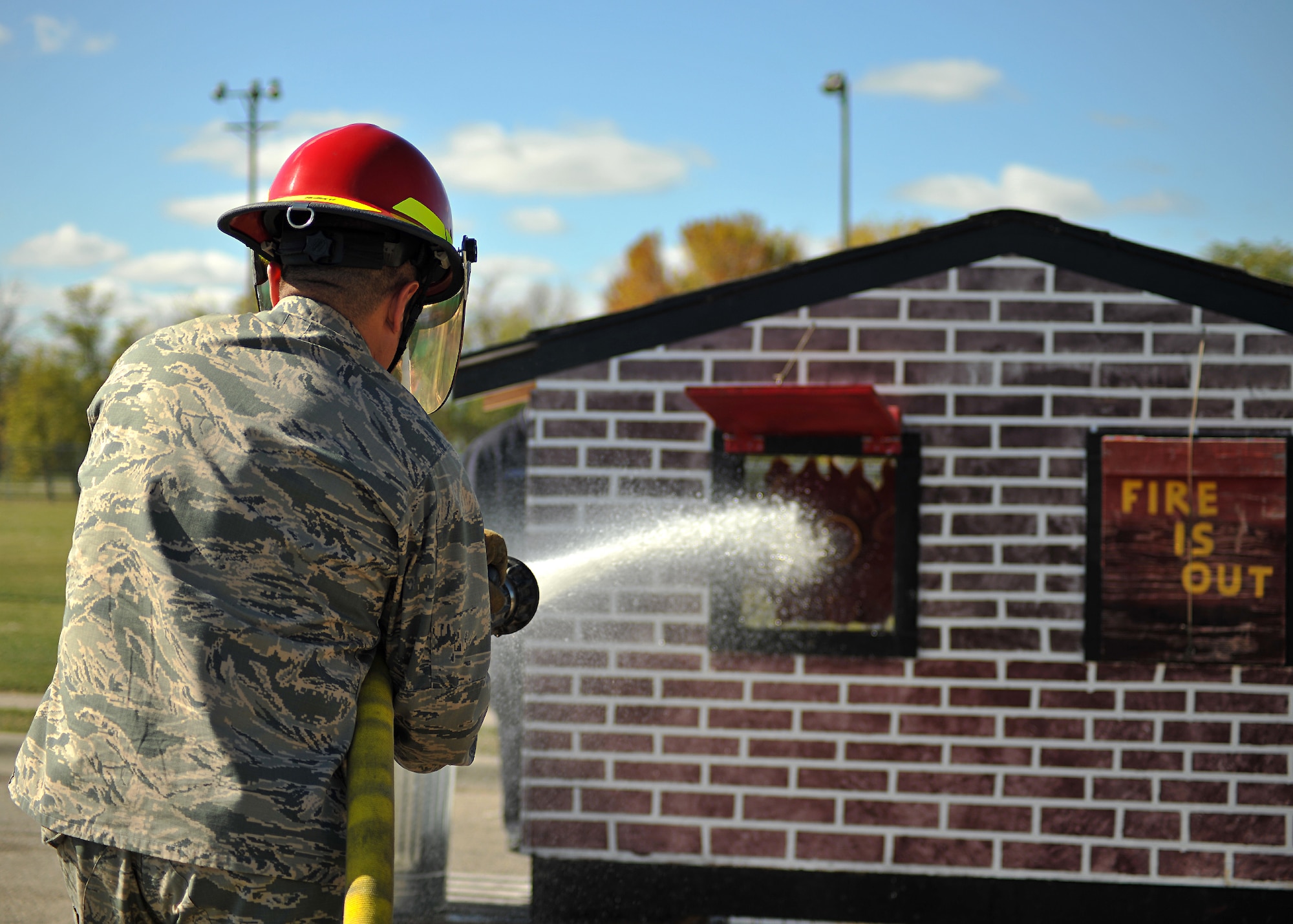 Col. Anthony Hernandez, 319th Mission Support Group commander, sprays a pressured hose at a target house during a timed fireman team challenge on Oct. 9, 2014, on Grand Forks Air Force Base, N.D. Hernandez was one out of ten participants. He completed the challenge in a time of one minute and 38 seconds. (U.S. Air Force photo/Senior Airman Xavier Navarro)