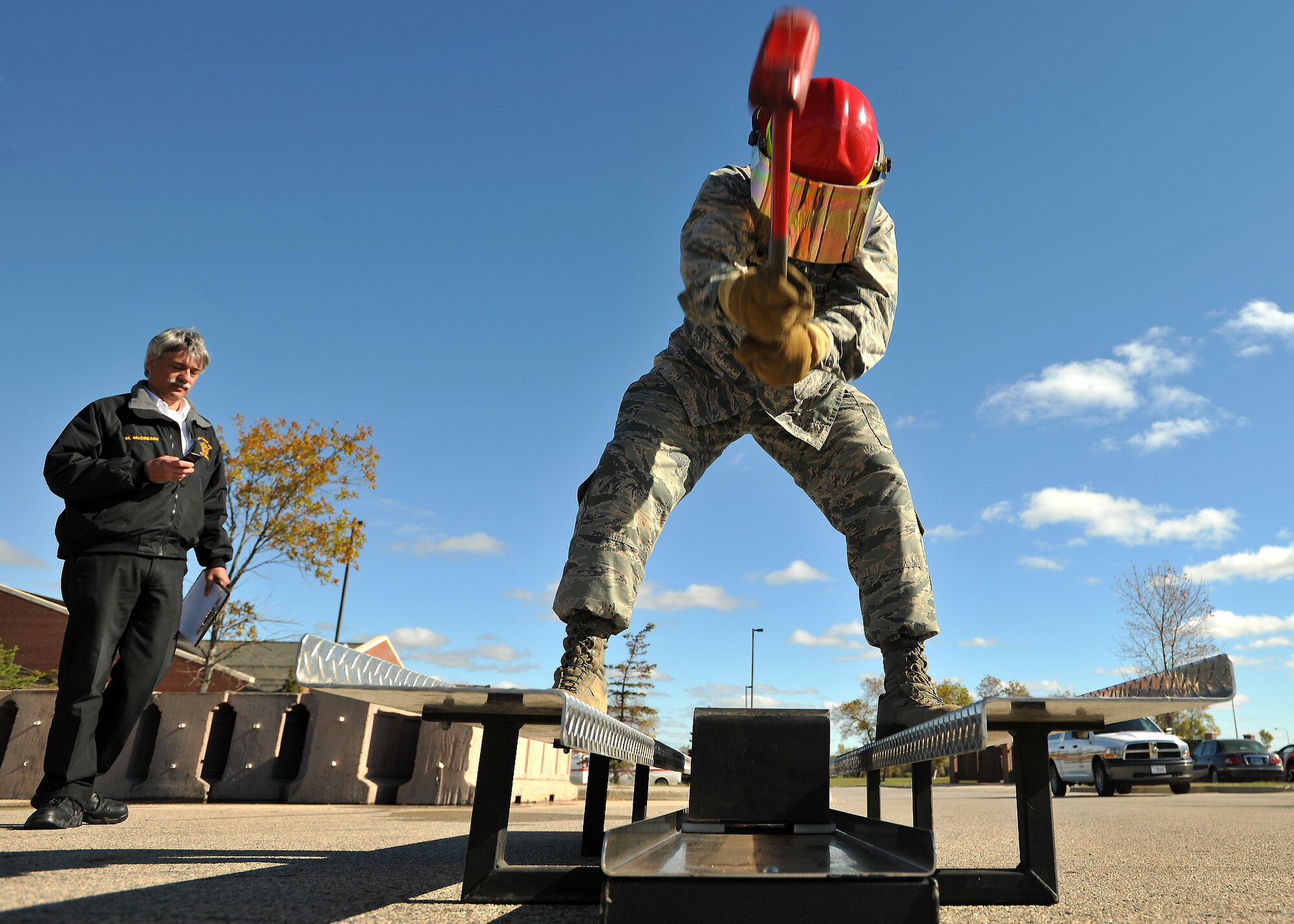 Grand Forks Air Force Base Fire Department Assistant Fire Chief Merle McCreary, keeps time on a stop watch, while Maj. Frank Burks, 319th Comptroller Squadron commander, hammers his way on a Kaiser sled during a timed fireman team challenge on Oct. 9, 2014, on Grand Forks AFB, N.D. Burks and Master Sgt. Daniel Shannon, 319th Air Base Wing Flight Safety superintendent, took 1st place with both times combined at two minutes and fifty seconds. (U.S. Air Force photo/Senior Airman Xavier Navarro)