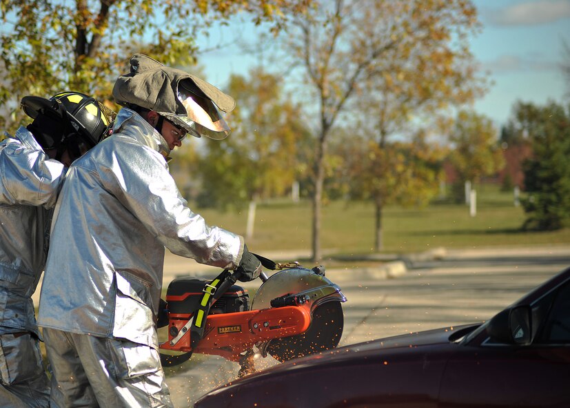 Airman 1st Class Brian Pierson, 319th Civil Engineer Squadron, uses a K-12 FD Fire/Rescue Saw to cut into the front hood of a car during an extraction demonstration on Oct. 9, 2014, on Grand Forks Air Force Base, N.D. The car extraction showed different tools and techniques that firemen use to safely and quickly remove a victim from the vehicle of an accident. (U.S. Air Force photo/Senior Airman Xavier Navarro)