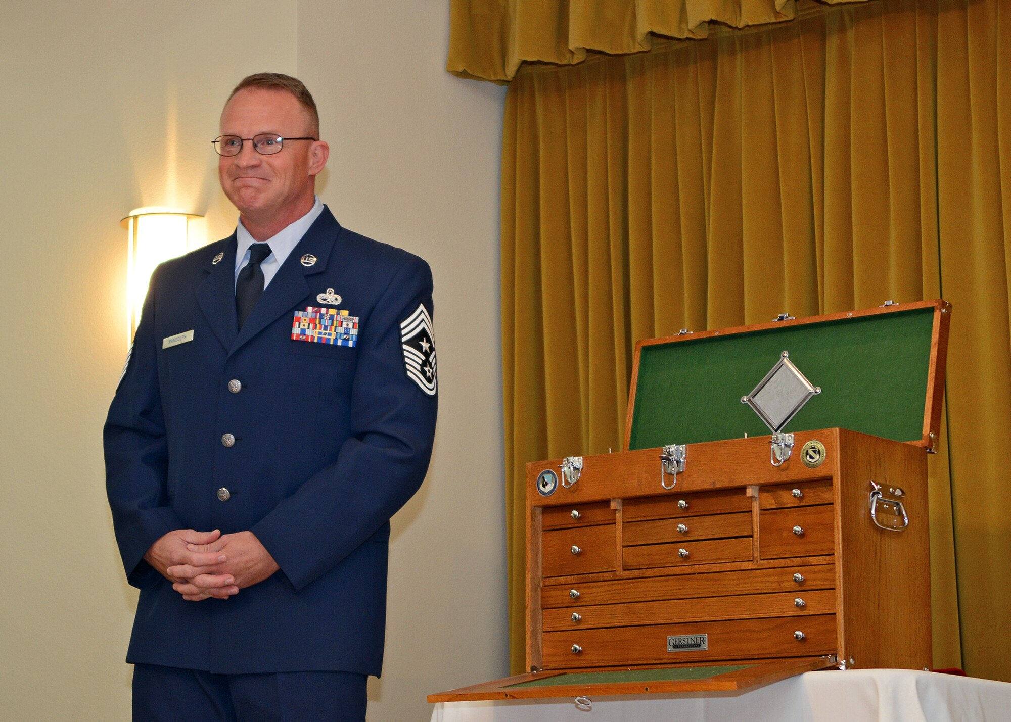 Chief Master Sgt. Brian Randolph stands next to a wooden tool box presented to him during his retirement ceremony Oct. 15 at Club Muroc. The tool box was presented by Brig. Gen. Michael Brewer, 412th Test Wing commander. Randolph has served the Air Force for 30 years, the last two as the 412th TW command chief where he served as the principle advisor to Brewer on matters concerning morale, welfare, discipline, training, fitness and effective utilization of the wing's 12,000 military, civilian, contractor personnel and their families.

Randolph was a maintainer by trade and has deployed to several locations and served as maintenance group superintendent in support of Operation Iraqi Freedom, Enduring Freedom, Joint Task Force-Horn of Africa, and most recently, Afghanistan. 
(U.S. Air Force photo by Jet Fabara)