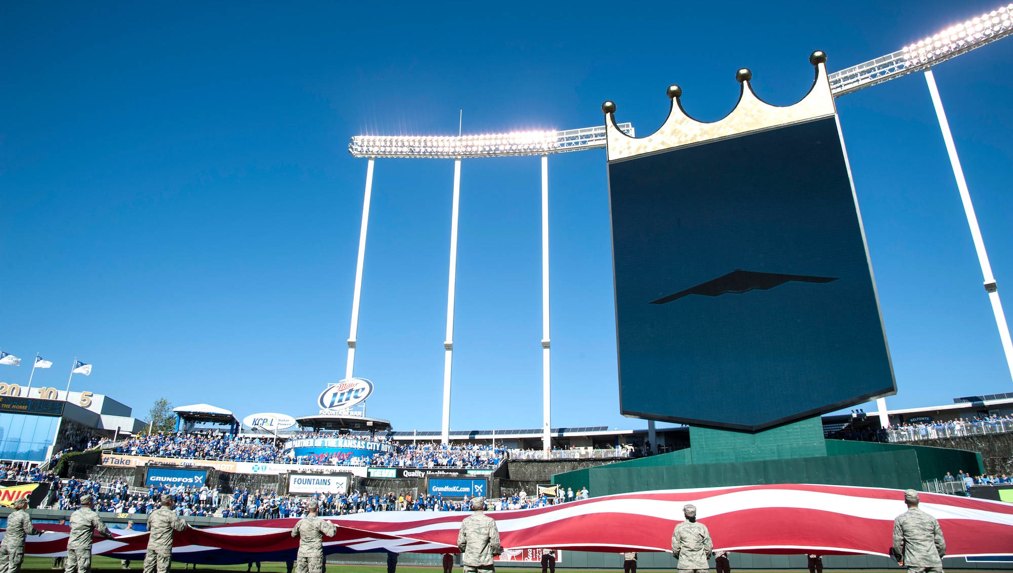 Airmen from the 509th Bomb Wing and 131st Bomb Wing at Whiteman Air Force Base, Mo., hold the American flag during the Royals vs. Orioles baseball game at Kauffman Stadium in Kansas City, Mo., Oct. 15, 2014. A B-2 Spirit stealth bomber made an appearance during the pre-game activities, representing the U.S. Air Force to a packed stadium as well as a TV viewership of millions during Game 4 of the American League Championship Series. (U.S. Air Force photo by Staff Sgt. Brigitte N. Brantley/Released)